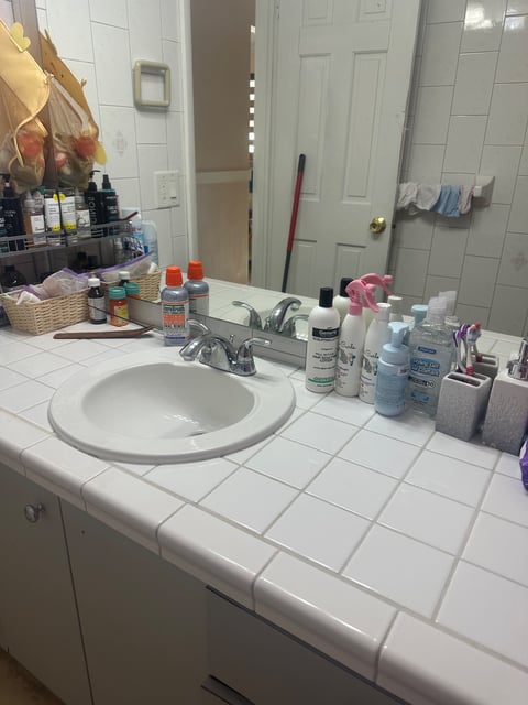 Bathroom counter with tiled sink, mirror, and toiletry bottles — Yohandra’s Clearning Services, Miami