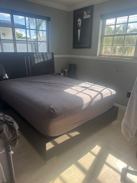 Bedroom with bare mattress on dark wood bed frame — Yohandra’s Clearning Services, Miami