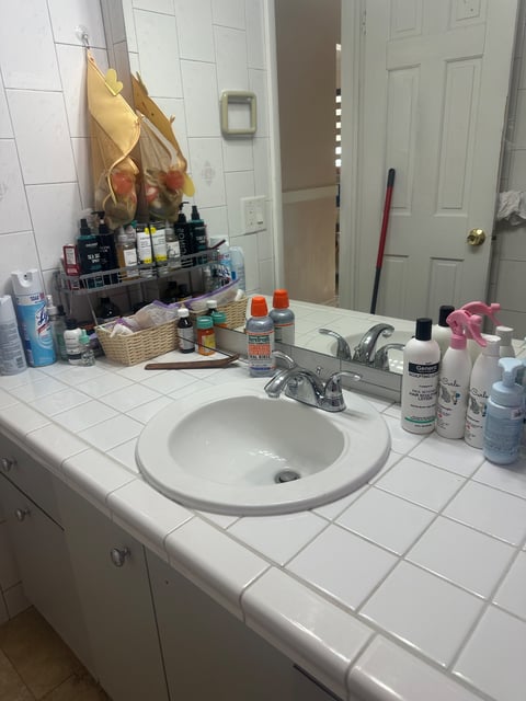 Bathroom counter with sink, mirror, and toiletry bottles — Yohandra’s Clearning Services, Miami
