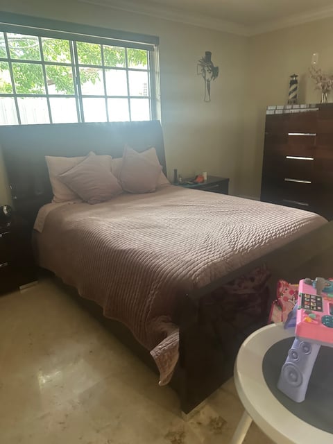 Bedroom with made bed, dark wood dresser, and tiled floor — Yohandra’s Clearning Services, Miami